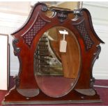 An Edwardian mahogany over mantle mirror, with broken swan neck pediment, having bevelled oval
