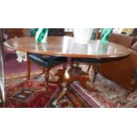 A Regency mahogany oval tilt top dining table, raised on turned pillar support, four sabre legs