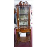 An Edwardian Sheraton revival serpentine front display case on stand,having broken swan neck