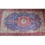 A 20th century Kashan carpet with central floral medallion, on a red and blue ground, contained by