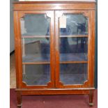 An Edwardian inlaid mahogany display cabinet, with bevelled glass panels, raised on tapered legs and