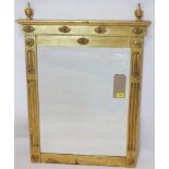 A gilt painted wall mirror, with urn finials above floral decoration and two flanking carved