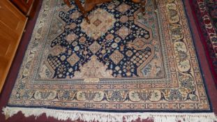 A signed Nepalese carpet with geometric floral motifs on a blue ground, contained by floral border