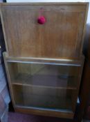 An Art Deco oak bureau bookcase, with compartmentalised interior above two sliding glass doors, on
