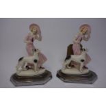 A pair of Art Deco porcelain figural studies of a young lady and her dog, on stepped silver plated