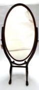 A 19th century mahogany oval cheval mirror, with boxwood inlay, raised on cabriole legs and castors,