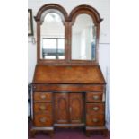 An early 18th century walnut bureau bookcase, the two arched mirrored doors enclosing drawers and