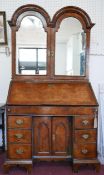 An early 18th century walnut bureau bookcase, the two arched mirrored doors enclosing drawers and