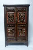 A Chinese hardwood side cabinet with two doors having carved gilt wood and lacquered panels, H.100