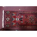 A North East Persian Meshad Belouch runner, triple pole medallion with repeating petal motifs on