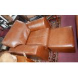 A contemporary brown leather armchair and matching stool