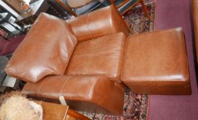 A contemporary brown leather armchair and matching stool