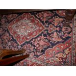 A fine Sarouk rug, with central floral medallion, on a red and blue ground, contained by floral