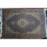 A part silk Tabriz rug, with floral medallion, on a blue and beige ground, contained by floral