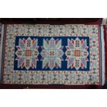 A Kazak rug with triple geometric medallion, on a blue ground, contained by geometric border on a