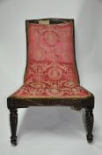 A carved mahogany lounger chair raised on castors