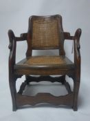 A south east Asian teak chair with cane seat and backrest and swan neck handles