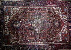 An antique Heriz carpet, with central geometric medallion, on a red, blue and cream ground,