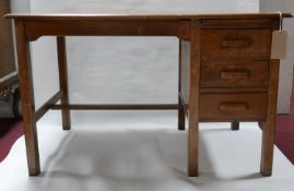 An Edwardian oak desk with three drawers and brush slide, H.76 W.121 D.68cm