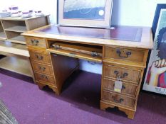 A 20th century pedestal desk, with red leather skiver above central sliding shelf flanked by two