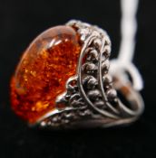 A large sterling silver and oval amber ring, the silver pierced mount in the form of detailed