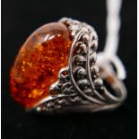 A large sterling silver and oval amber ring, the silver pierced mount in the form of detailed