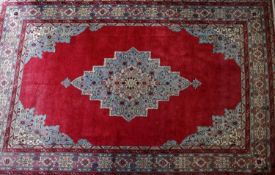 A large Tabriz carpet with central floral medallion, on a red ground, contained by geometric