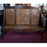 An Arts & Crafts walnut settle with cane seat and backrest, H.118 W.151 D.54cm
