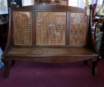 An Arts & Crafts walnut settle with cane seat and backrest, H.118 W.151 D.54cm