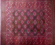 A large Turkmen Bokhara carpet, with central repeating geometric motifs on a red ground, contained