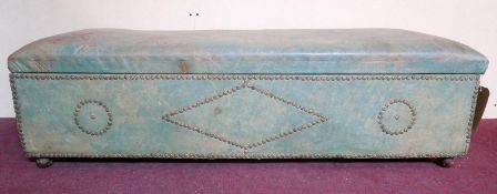 An early 20th century stud bound distressed green leather ottoman, raised on bun feet, H.35 W.127