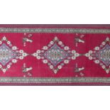 A South West Persian Abadeh runner, repeating stylised gul motifs on a rouge field, within