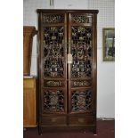 A Chinese hardwood cabinet with two doors having carved gilt wood and lacquered panels, H.166 W.89