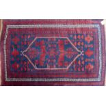 A mid 20th century Turkish rug, with geometric floral medallion, on a red and blue ground, contained