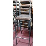 A set of 6 industrial black steel bar stools with brown leather seats