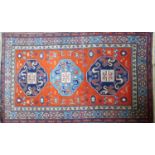 A 20th century Kazak rug, triple geometric medallion on a red & blue ground, contained by