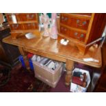 An early 20th century pine kitchen dining table, with two leaves, raised on turned legs and castors,