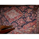 A fine Sarouk rug, with central floral medallion on a red and blue ground, contained by floral