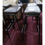 A set of 4 industrial black steel bar stools with brown leather seats