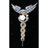 A yellow gold caduceus style brooch pave-set with turquoise and diamonds and centrally-set with a