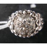 An 18ct white gold and diamond cluster ring to a pierced outer mount and wide, ribbed shoulders,