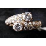A boxed 18ct yellow gold and brilliant-cut diamond cross-over ring set with 2 round brilliant cut