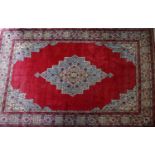 A large Tabriz carpet with central floral medallion on a red ground, contained by geometric floral