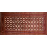 A North East Persian Turkoman rug, repeating stylised Tekkeh motifs on an ivory field within