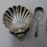 A silver shell shaped salt dish with matching spoon by A.C & Ss LD