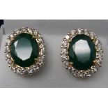 A boxed pair of 18ct yellow gold, emerald and diamond cluster stud earrings, each earring composed