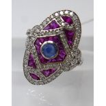 An 18ct white gold Art Deco style diamond ruby and sapphire ring, composed of an oval-shaped mount