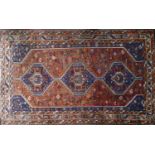 An antique Shiraz carpet with triple geometric diamond medallions, on a blue and orange ground,