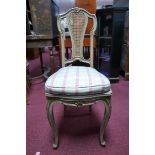 A grey painted French chair, parcel gilded, with cane seat and back rest, raised on cabriole legs