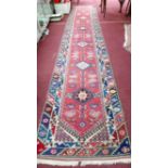 A 20th century Persian runner, with 6 diamond pole medallion, on a red ground, contained by
